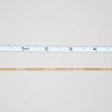 Gold chain with a ruler for scale on a white background