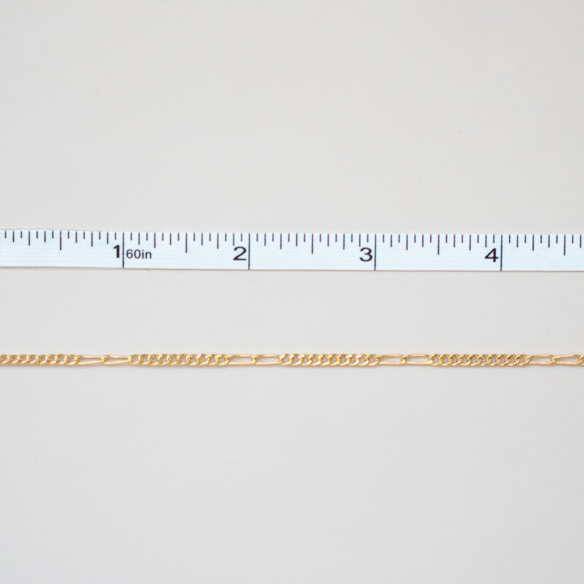 Gold chain with a ruler for scale on a white background