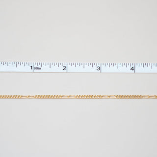 Gold chain with a ruler for scale on a white background
