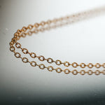 Gold chain necklace reflecting on a surface.