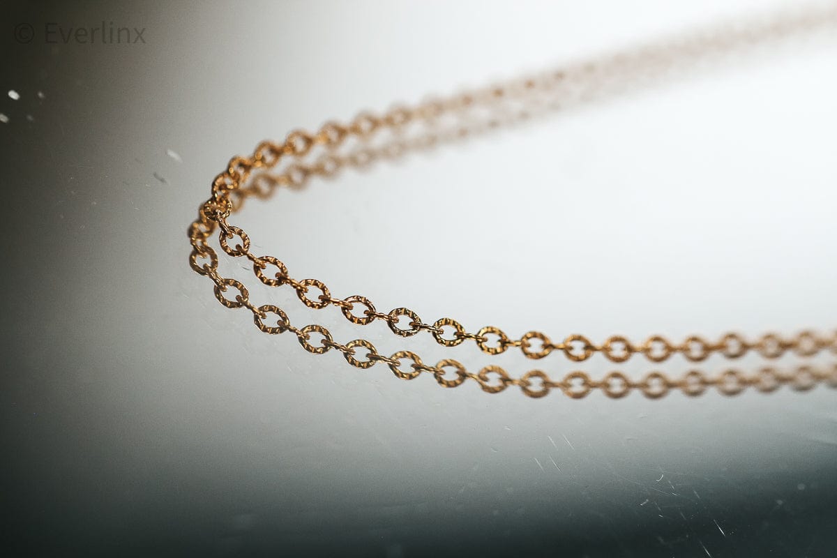 Gold chain necklace reflecting on a surface.