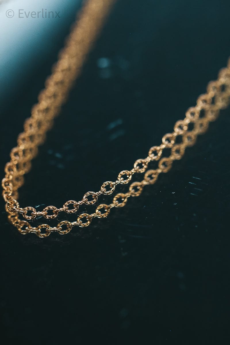 Gold chain necklace on a dark surface.