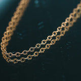 Gold chain necklace on a dark surface.