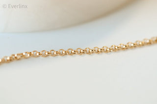 Gold chain necklace on a white surface.